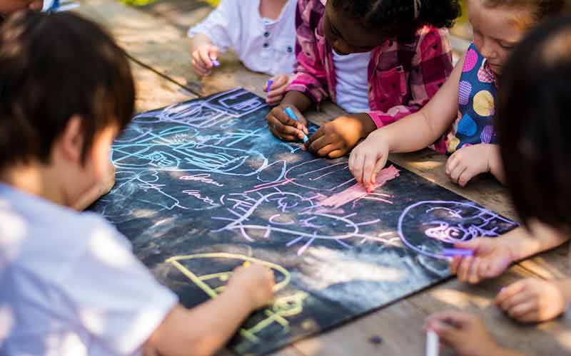 children drawing on chalkboard