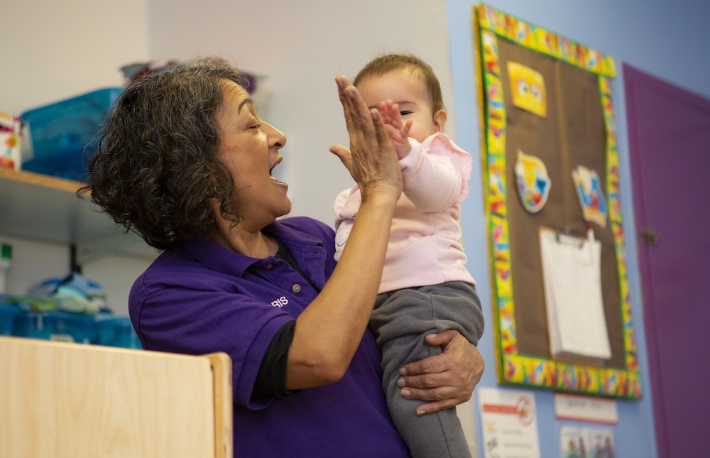 A teacher and infant giving a high five together