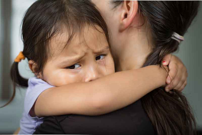 Young toddler crying in caregivers' arms