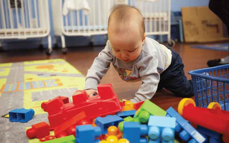 Baby looking at pile of big building blocks in classroom