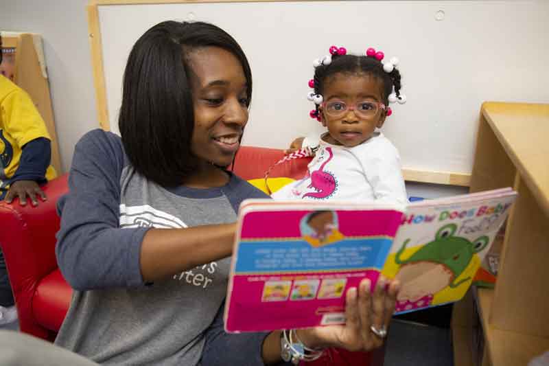 Teacher and baby look at book about feelings together
