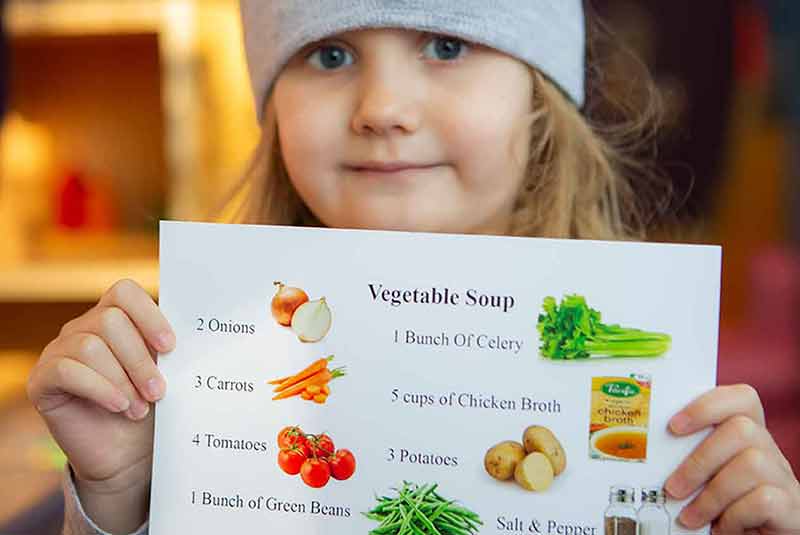 girl holding up vegetable soup recipe