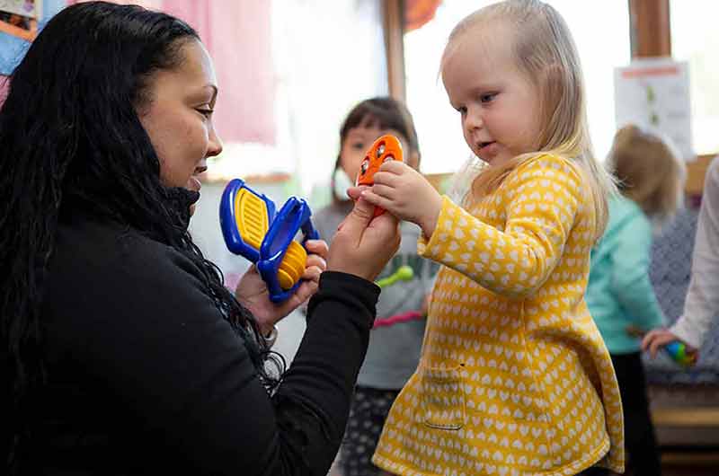 A teacher explaining her thoughts about an instrument to a toddler