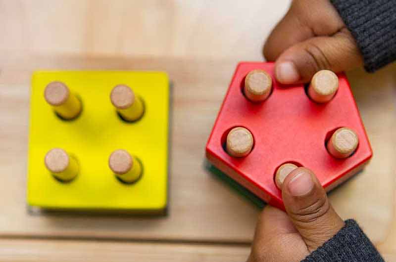 Toddler placing shape with 5 holes on puzzle