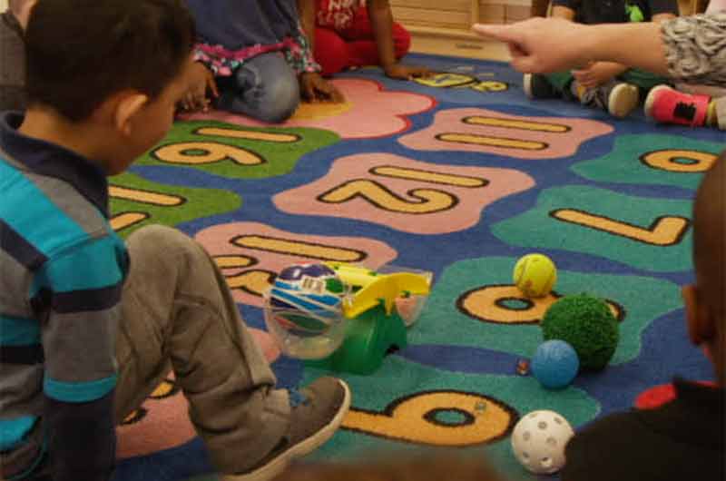 A child near a kids scale with two balls in it