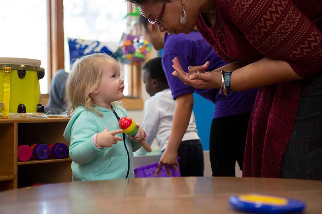 A toddler and an educator engaged in conversation