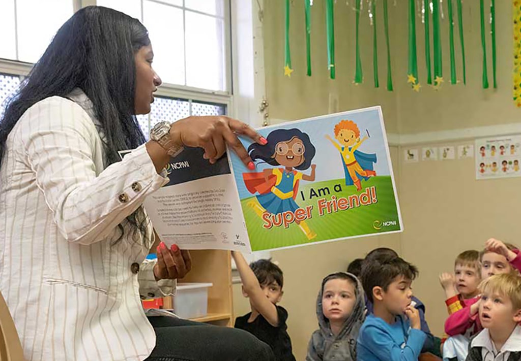Teacher reads a copy of I am a Super Friend story to children during circle time