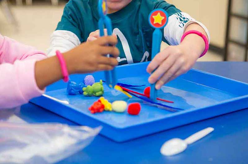 Two children engaged in a sorting activity with tweezers