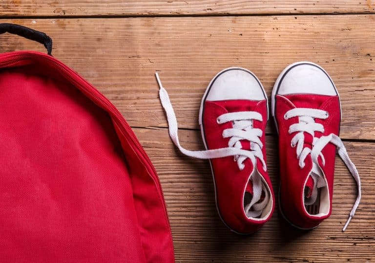 Aerial view of child-sized shoes beside backpack