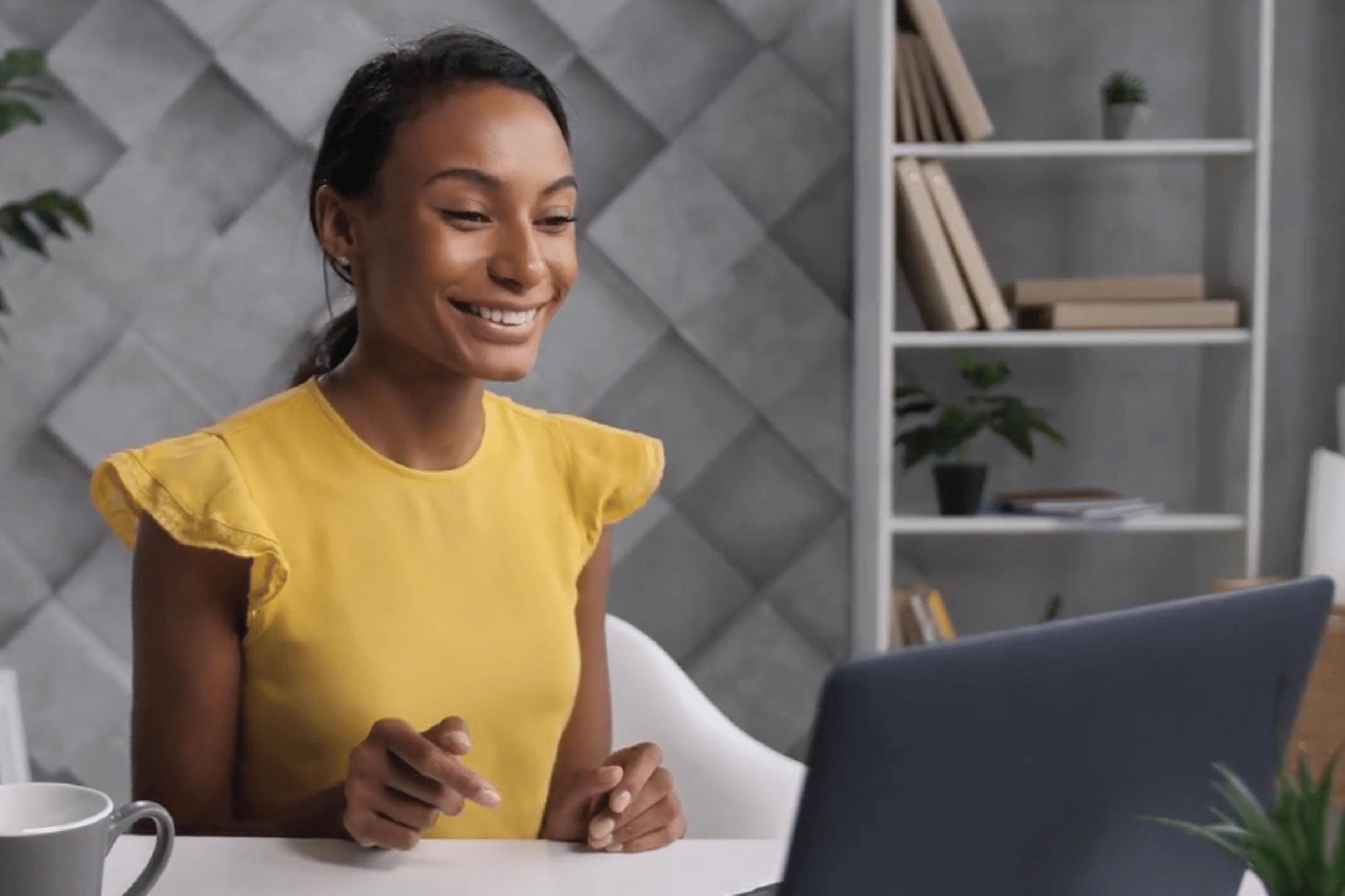 webinar Woman sits at a desk looking at a computer and smiling
